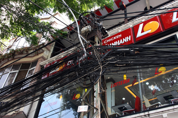 Birdsnests of tangled electrical wires run above the streets in Saigon