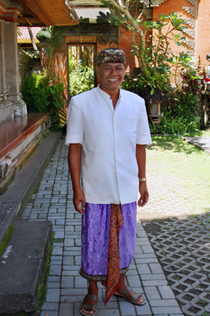 Balinese man wears a traditional sarong, sash, and saput