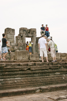 Crowds climb on ruins at Phnom Bakheng temple Angkor Wat