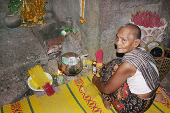 Nun inside a temple within the Angkor Wat complex provides incense to worshipers