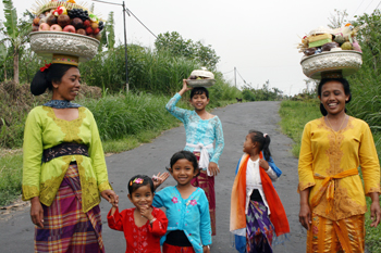 Women in traditional dress carryofferings to temple in bali