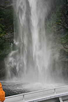Motoring beneath a raging waterfall at Milford Sound New Zealand