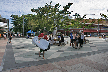 Surfers walk through the main plaza on their way to the ocean in Cairns Australia