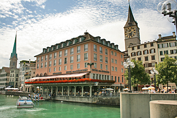 The clock tower of St. Peter's Church glowers over buildings lining the Zurich River Switzerland