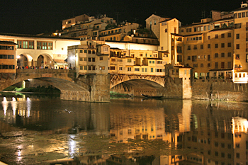 Ponte Vecchio reflects in River Arno at night in Florence Italy