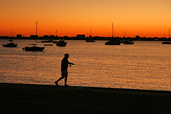 A lone fisherman casts from Bayfront Park as the sun sets over Sarasota Bay