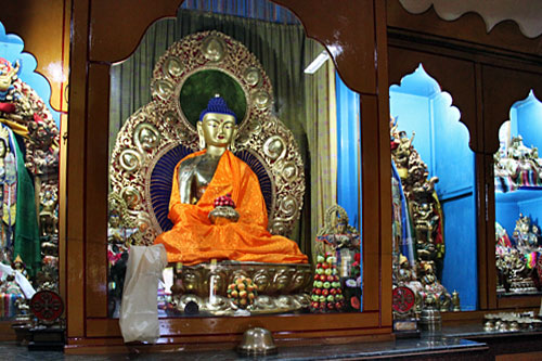 Buddha sits behind glass on altar at Shree Gaden Dhargay Ling Monastery