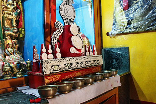 Yak butter carving and seven bowls of water sit in front of Buddha on the altar
