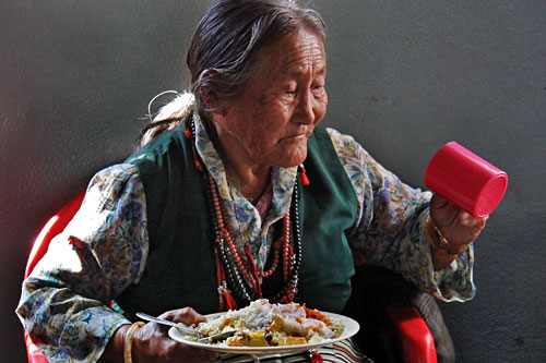 Tibetan woman enjoys meal at International Human Rights Day Celebration at Tashiling Tibetan refugee settlement in Pokhara, Nepal