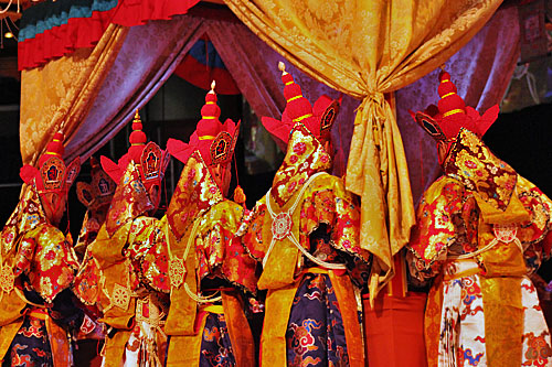 Elaborate robes and headgear of mnks praying at mandala platform