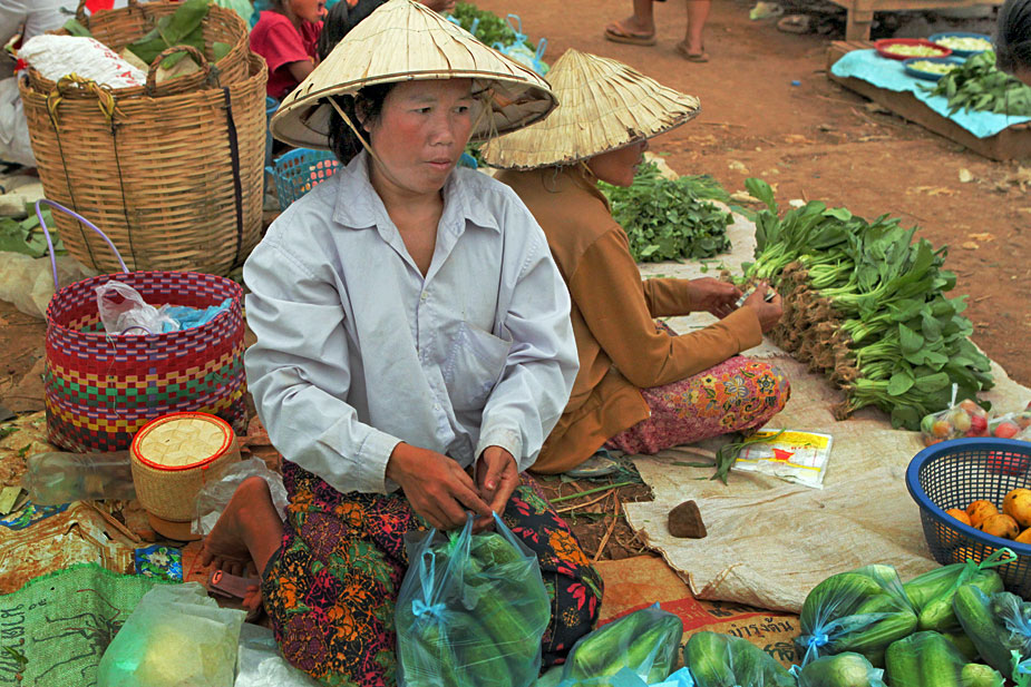 Women sell produce at market under blazng sun in Pakse, Laos