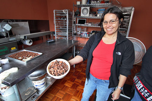 Maria holds a bowl of unroasted cacao beans