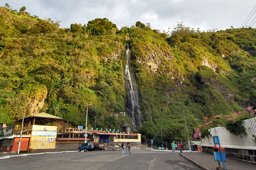 Waterfall cascades down mountainside and is channeled into Termas de la Virgen thermal baths in Baños de Agua Santa, Ecuador