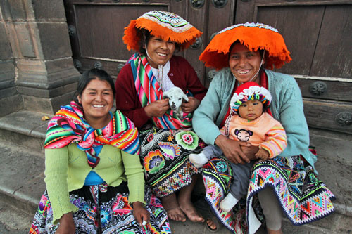 Quechua women on steps of Sato Domingo Church in Cusco, Peru pose for photos