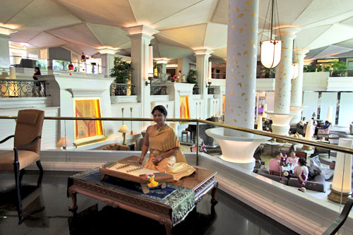 Musician plays soothing string music in lobby of Dusit Thani Hotel. Go see this luxurious hotel for its gardens, eat at the buffet, but stay at Lub-d Silom!