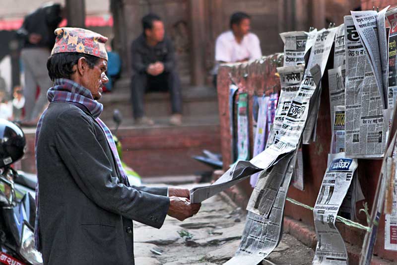 Man Reads Newspapers Posted on a Board in Durbar Square, Kathmandu, Nepal
