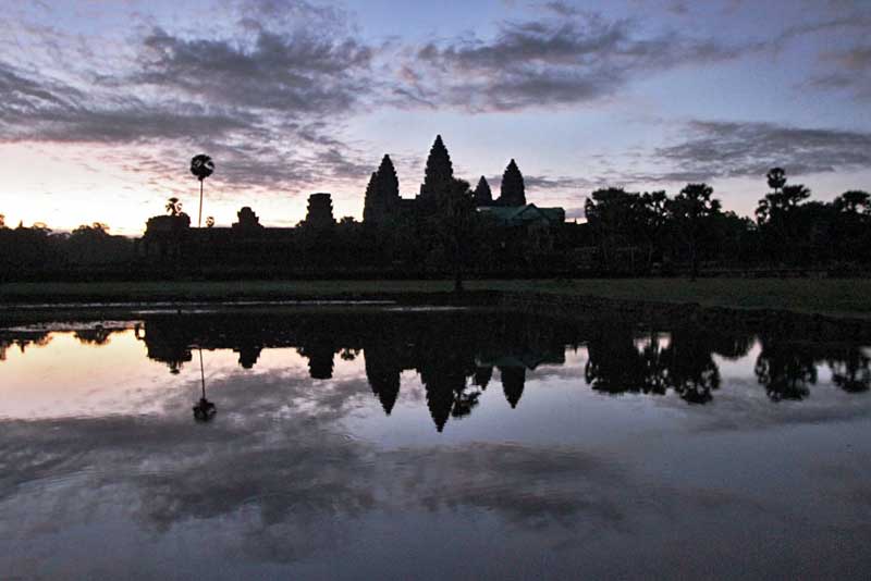 Sunrise Casts Mirror Image of Famous Spires of Angkor Wat Temple on Reflecting Pond