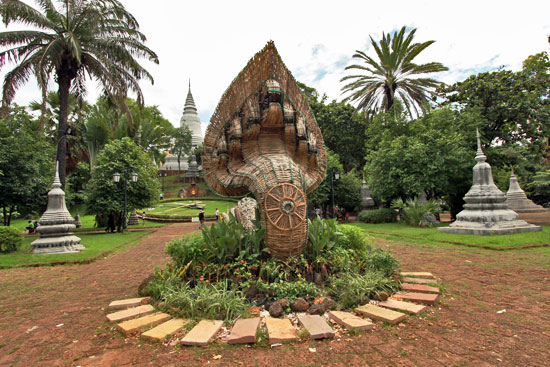 Peaceful park is home to Wat Phnom, seen in background behind giant wicker seven-headed Naga (snake)