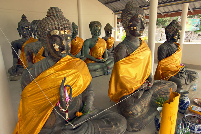 Close-up of rare metal Buddha statues, some of which have tarnished green