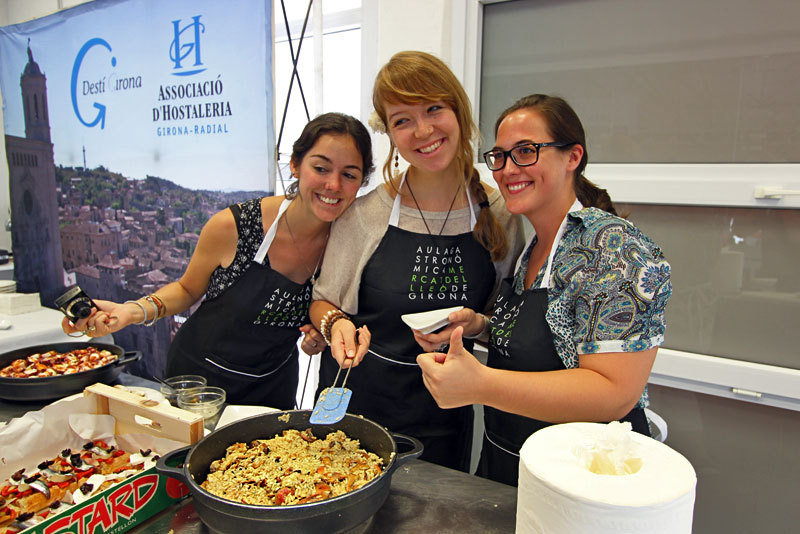 Three Cooking Class Participants in Girona, Spain, Proudly Display Their Vegetable Paella