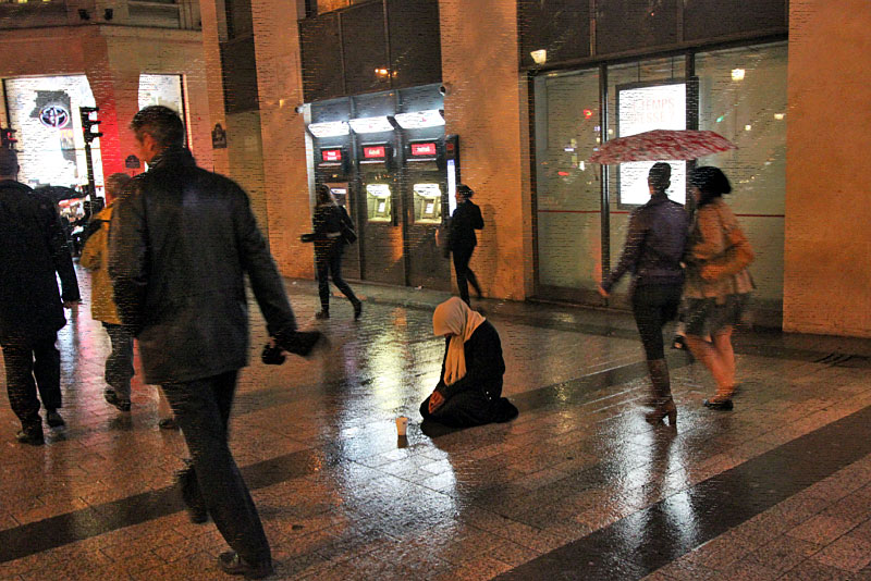 Beggar on the Champs Elysee, on a Rainy Night in Paris, France
