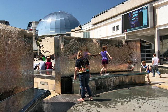 Kids play in the fountains in Millennium Square in downtown Bristol, England