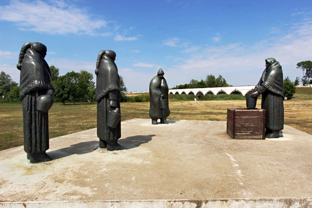 Sculpture of early Hungarian residents, with Nine-Arched Bridge in the background at Hortobagy National park in Eastern Hungary