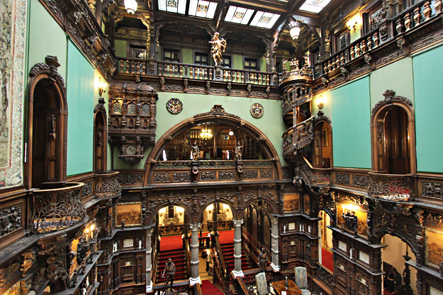 Hall of Honor in Peles Castle features a wooden spiral staircase, Roman columns, and an Archbishop's Prayer Box