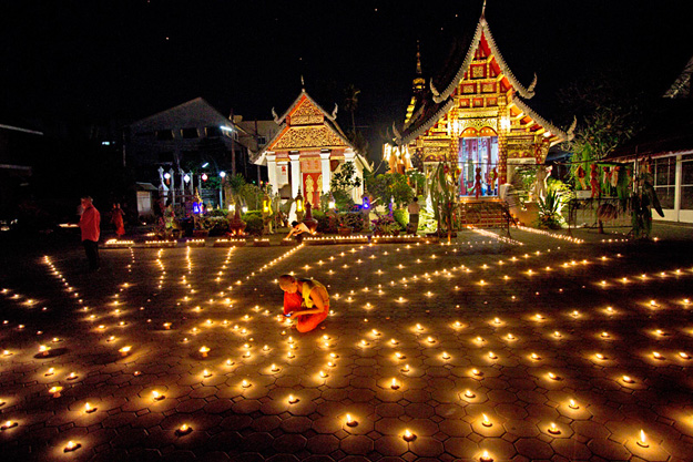 Monks tend to candles placed in a starburst pattern in the courtyard of Wat Muentoom during Yi Peng Festival in Chiang Mai