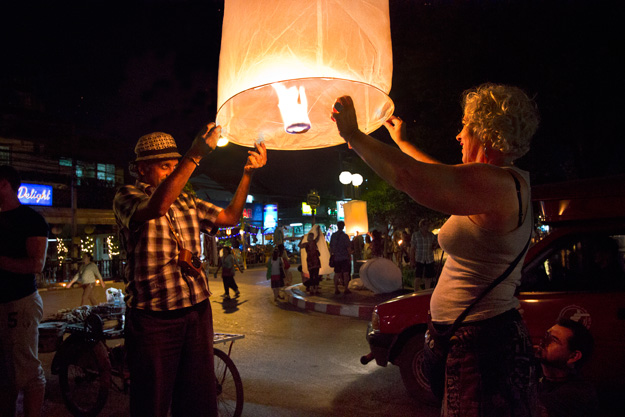 Tourists join in the fun of Yi Peng by lighting and sending aloft a lantern