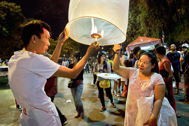 Thais take a break from work to launch a rice paper lantern during the Yi Peng Festival