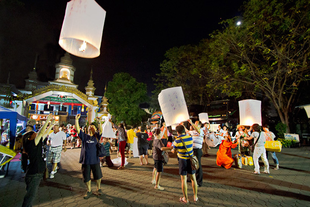 The grounds of Wat Umokot are filled with festival-goers sending paper lanterns into the night sky