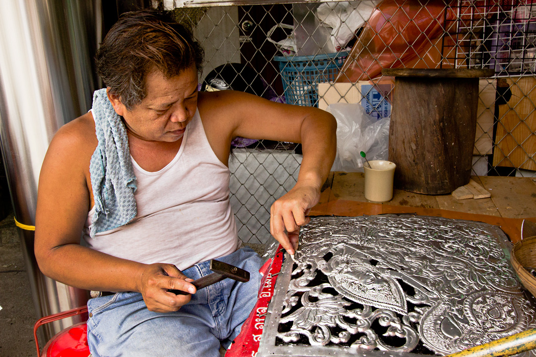 Worker cuts elaborate designs into sheets of aluminum in Chiang Mai, Thailand