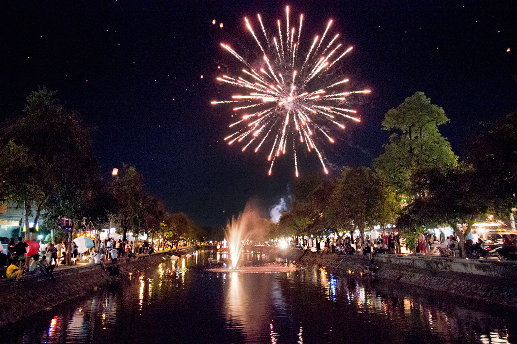 Paper lanterns take flight amidst fireworks over the canals of Chiang Mai, Thailand