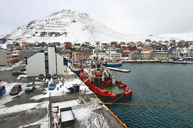 Hurtigruten's big ship docks alongside other working boats in the harbor at Honningsvag