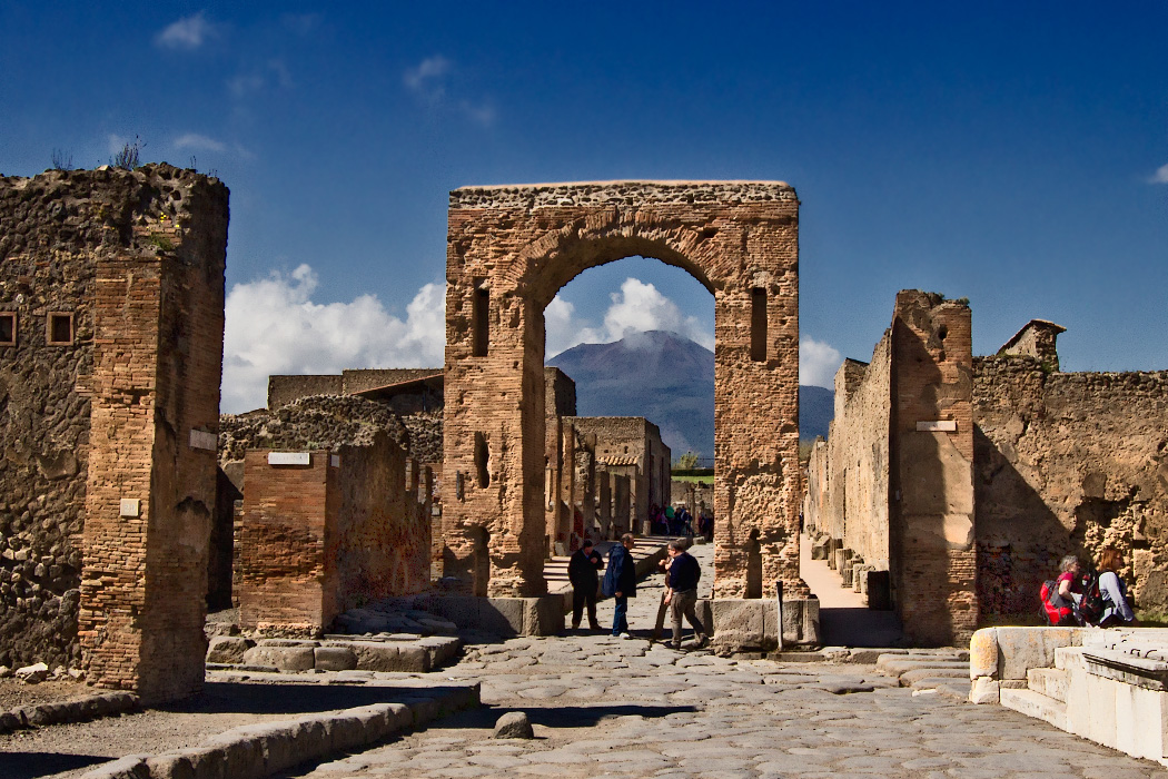Honorary Arch in the ruins of Pompeii, Italy, frames the blown-off top of Mount Vesuvius, which erupted in 79 AD and buried the town under tons of volcanic ash