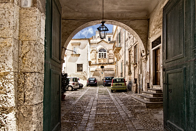 View through an archway to an interior courtyard of a private residence in Noto, Sicily