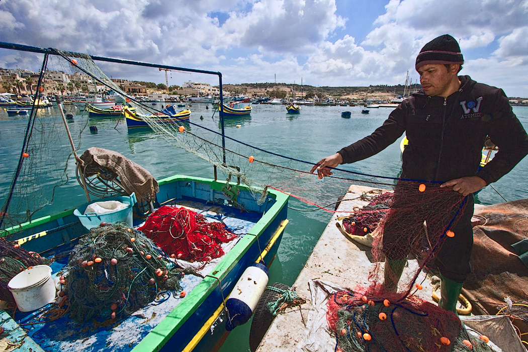 Fisherman in the village of Marsaxlokk, Malta inspects his nets after bringing in the day's catch