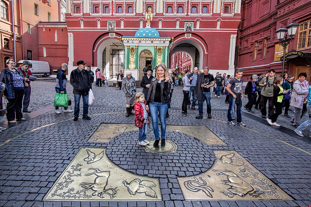 Visitors at the entrance to Red Square toss coins while standing on "Zero Kilometer," the place from which all distances in Moscow are measured