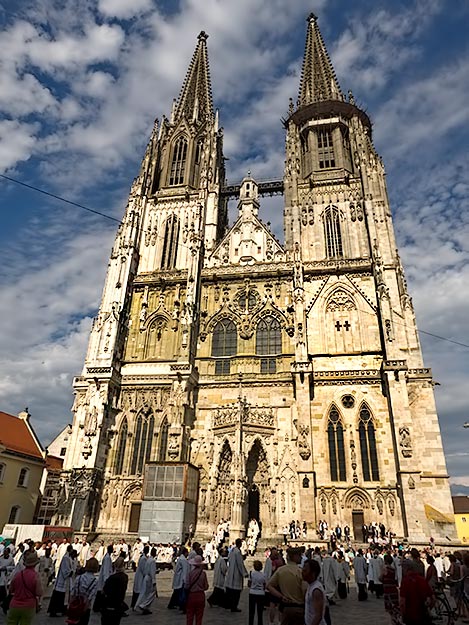 Altar boys in white robes stream out of St. Peter Cathedral in Regensburg, Germany