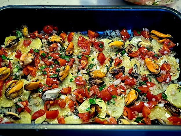 Tajeddha casserole, with steamed mussels, sliced potatoes, onions, tomatoes, parsley, sweet Pecorino cheese, and a scattering of rice