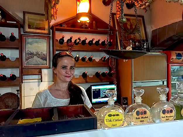 Argita Prifti behind the bar of Oda Restaurant. The bottles of homemade rakia in the foreground are still made the traditional way, in a copper still in an attached outdoor kitchen