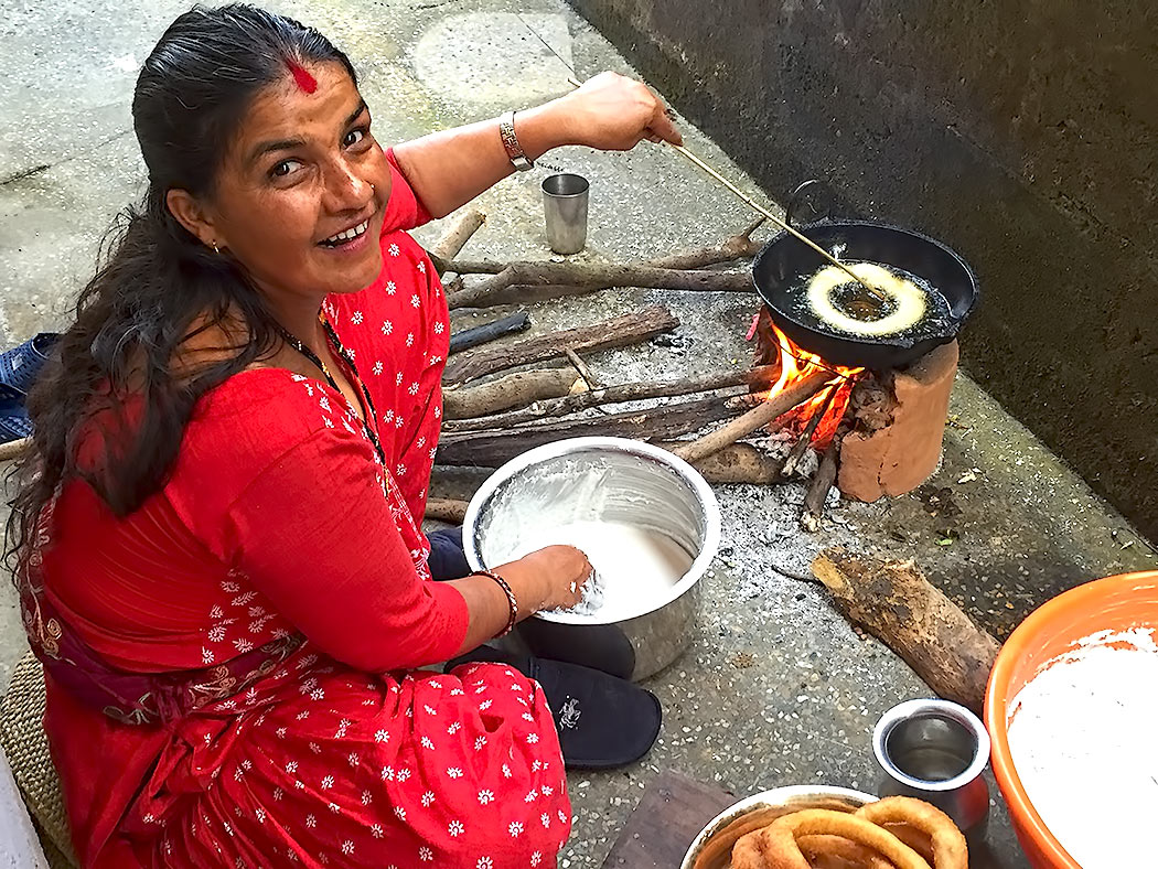 Nepali Woman makes fried Sel Roti rice flour rings over an open fire during the Hindu holiday of Tihar in Pokhara, Nepal