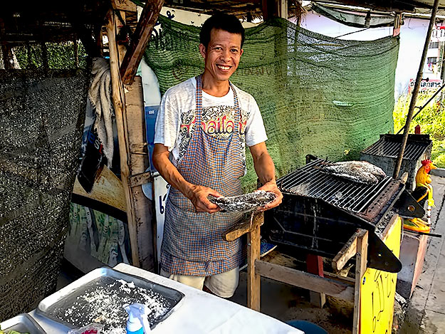 Street vendor prepares salted fresh fish for cooking over a charcoal grill
