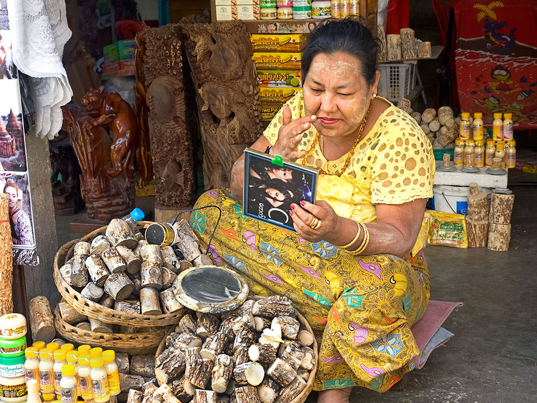 Shop owner at the Scott Market in Yangon, Myanmar, applies traditional Thanakha paste to her face. Made by grinding branches of the Thanakha tree into a powder and then adding water, the paste is used as a protection from the sun and as an enhancement to beauty