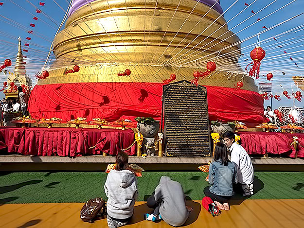 Worshipers offer merit-making gifts at the base of the giant stupa at the Golden Mount