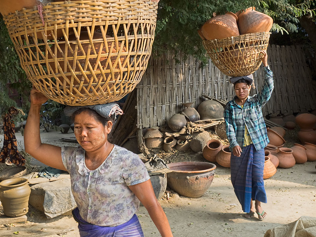 Women from Yandabo pottery making village near Mandalay, Myanmar, carry freshly fired pots down to the riverbank in preparation for shipping