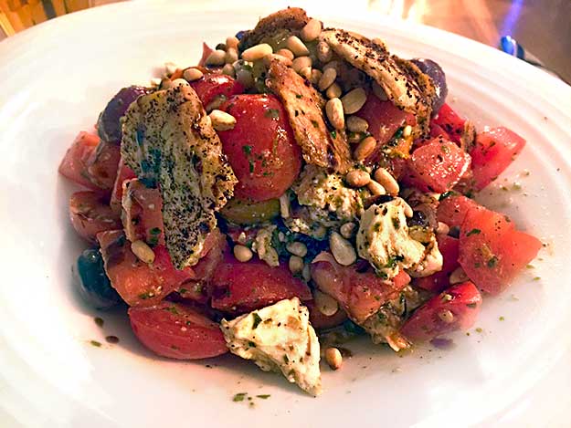 Salad of tomatoes, olives, fried mozzarella, roasted red peppers, pine nuts, and fried bread at Pasta Basta Restaurant in Jerusalem's Machane Yehuda Market