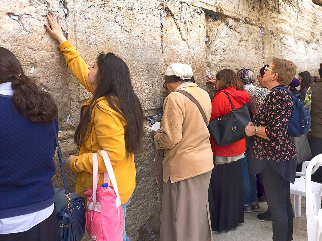 Worshipers at Western Wall in Jerusalem pray and stuff prayer-filled notes into cracks in the wall