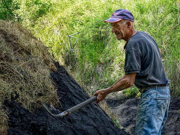 Carbonai Pietro Cruciani prepares to cover the kiln with soil and charcoal ash mixture